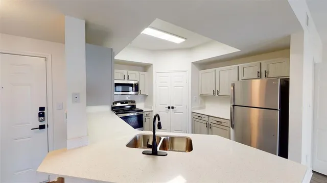 a view of a kitchen with a sink refrigerator and wooden floor
