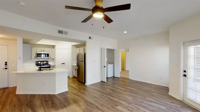 a view of an empty room with a window and wooden floor