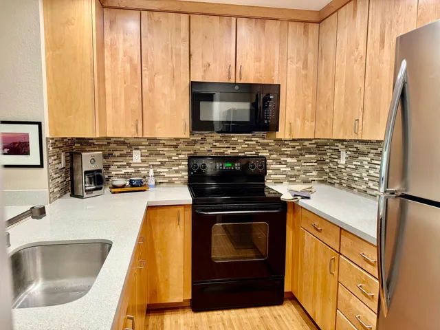 a kitchen with granite countertop a stove a sink and a microwave
