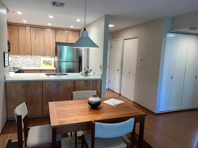 a kitchen with stainless steel appliances granite countertop a table chairs refrigerator a sink and dishwasher