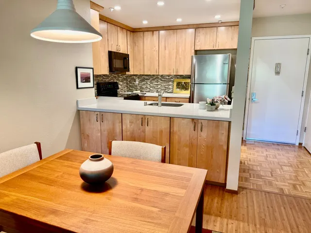 a kitchen with stainless steel appliances a dining table a refrigerator and a stove top oven