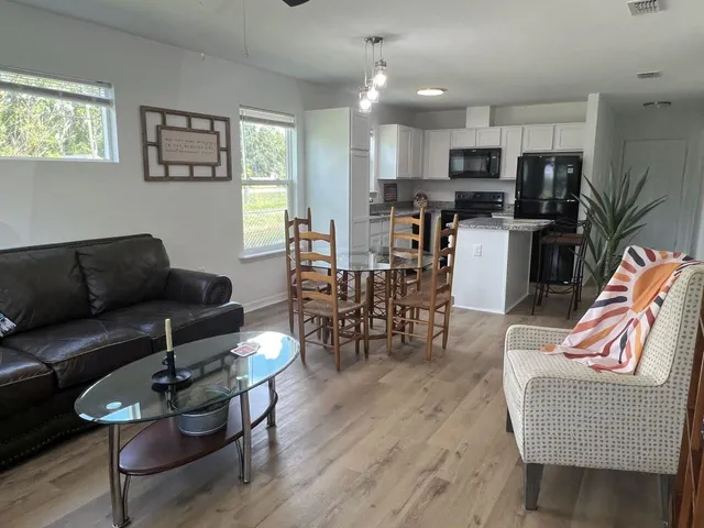 a living room with furniture kitchen view and a wooden floor
