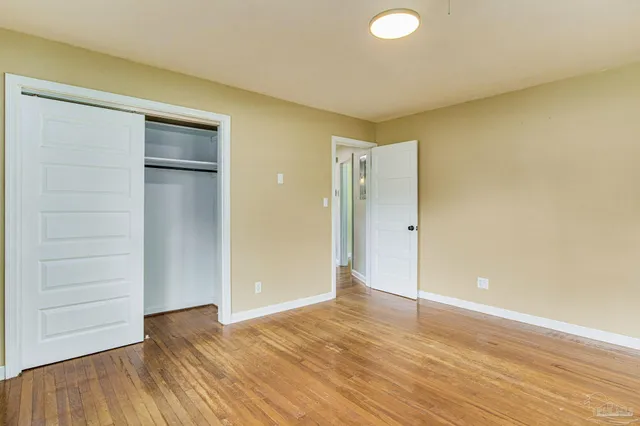 an empty room with wooden floor and closet