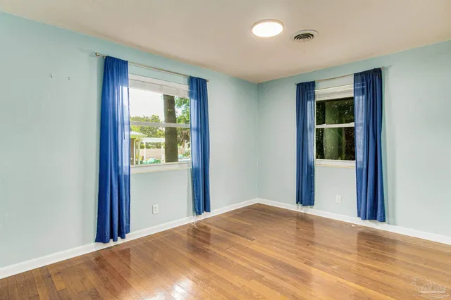 a view of a bedroom with wooden floor and windows
