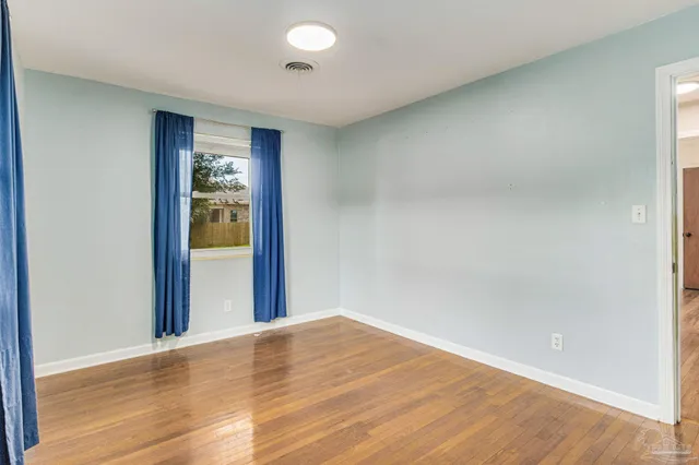 a view of empty room with wooden floor