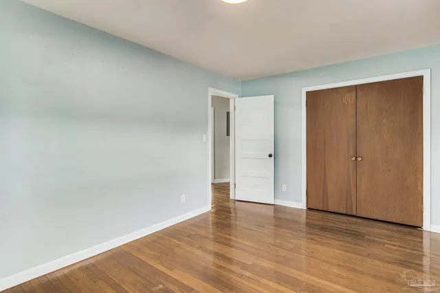 a view of an empty room with wooden floor and closet