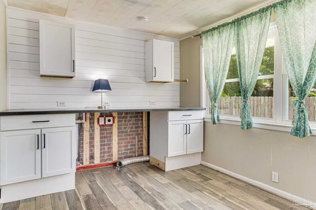 a kitchen with stainless steel appliances granite countertop a stove a sink and white cabinets with wooden floor