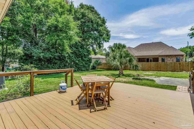 a view of a patio with table and chairs with wooden floor and fence