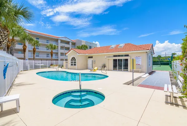a view of a swimming pool with a lawn chairs under palm trees