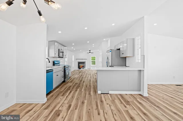 a view of a kitchen with kitchen island a sink wooden floor and a refrigerator