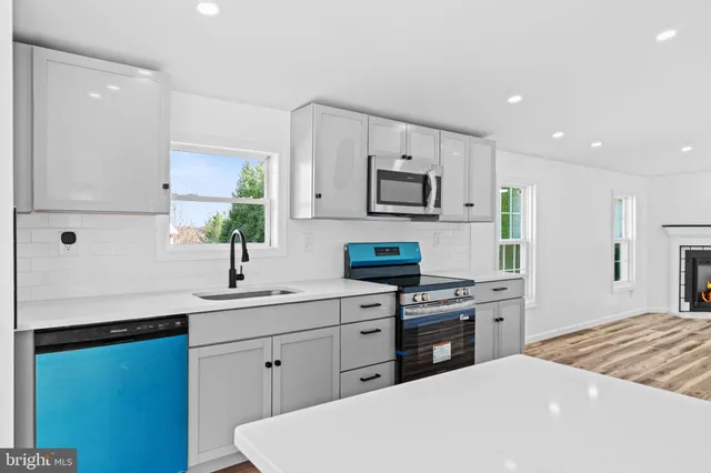 a large white kitchen with kitchen island a sink stainless steel appliances and cabinets
