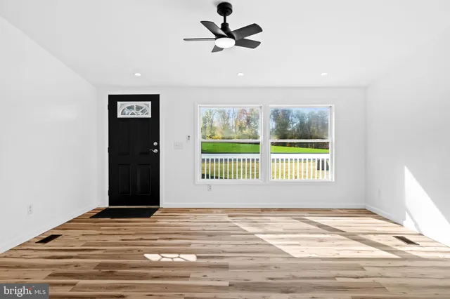 a view of an empty room with a window and wooden floor