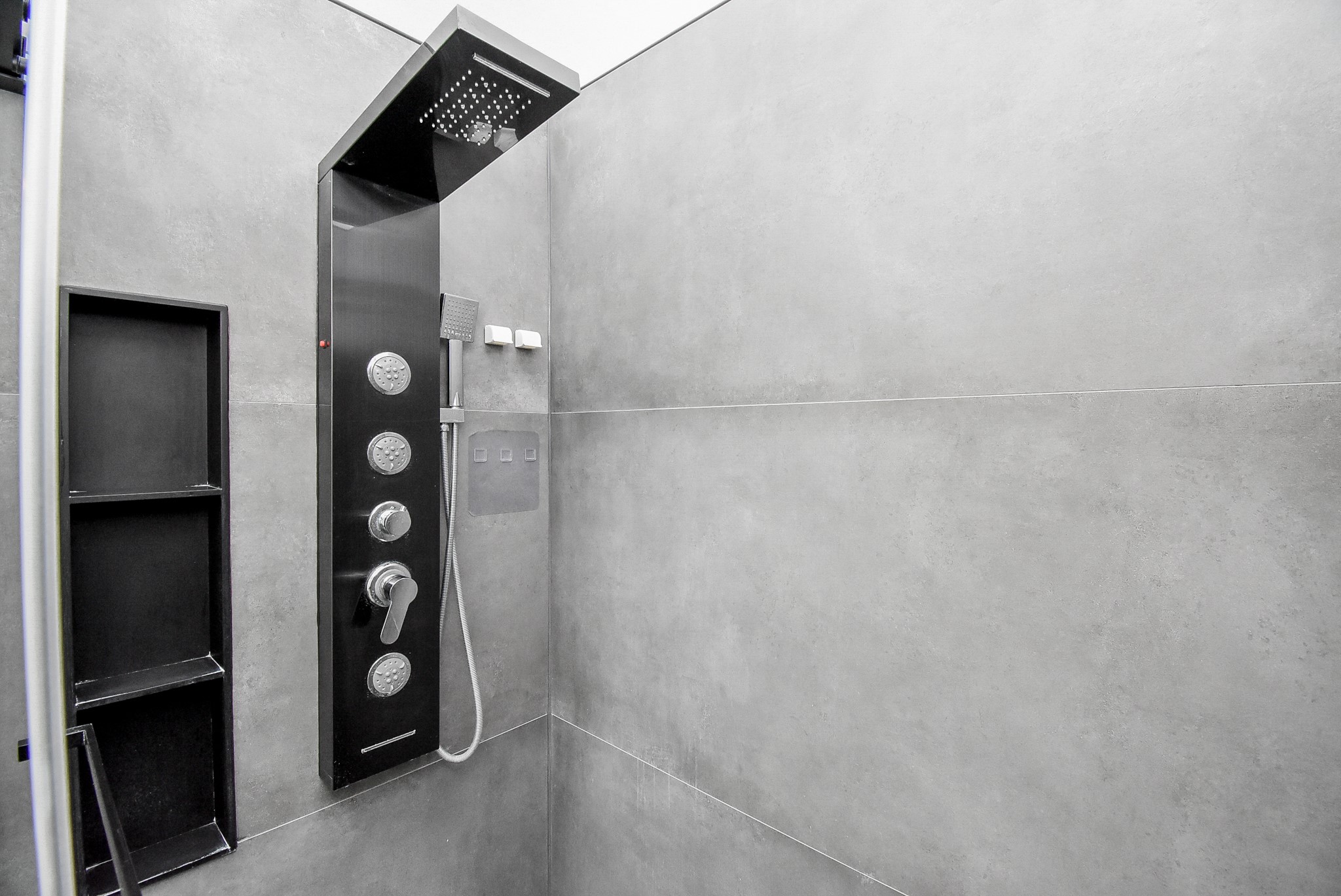 8715 Vinkins Road Houston, TX 77071 - Photo 33 of 48 Indulge in a spa-inspired walk-in shower featuring contemporary oversized tile, a frameless glass enclosure, a luxury multi-function shower panel with rainfall showerhead and body jets, plus built-in niches for added convenience.