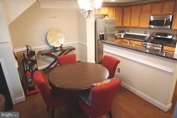 a kitchen with stainless steel appliances a stove a refrigerator a sink a dining table and chairs with wooden floor