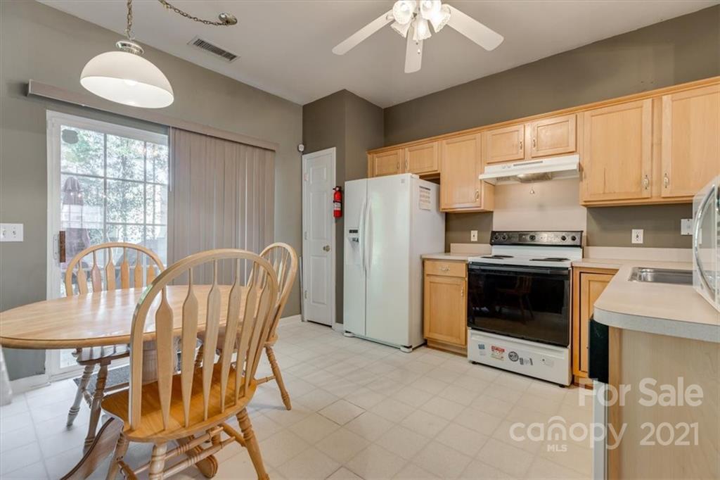 14014 Dingess Road Charlotte, NC 28273 - Photo 14 of 38 a kitchen with stainless steel appliances granite countertop a stove a refrigerator a microwave a dining table and chairs with wooden floor