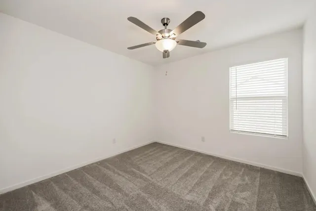an empty room with ceiling fan and window