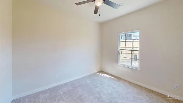 an empty room with a window and a fan