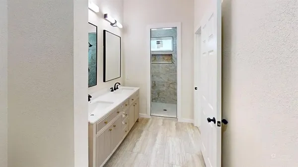 a bathroom with a double vanity sink a mirror and a shower
