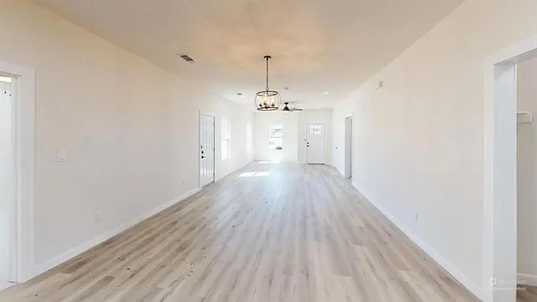 a view of a hallway with wooden floor and chandelier