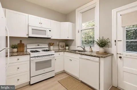 a kitchen with granite countertop white cabinets and white appliances