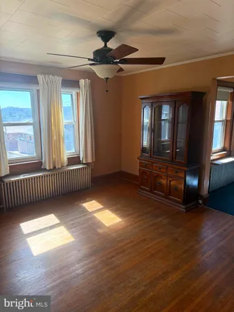 a view of an empty room with a window and wooden floor