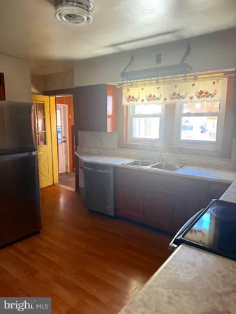 a kitchen with stainless steel appliances wooden floor and a large window