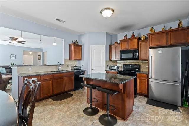 a kitchen with stainless steel appliances granite countertop a refrigerator a stove a sink dishwasher and a refrigerator with wooden floor