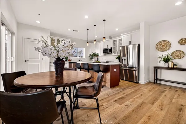 a kitchen with stainless steel appliances kitchen island granite countertop a dining table chairs and a refrigerator