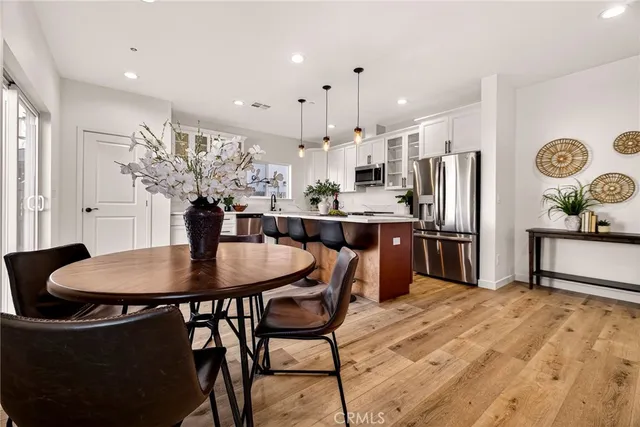 a kitchen with stainless steel appliances kitchen island granite countertop a dining table chairs and a refrigerator