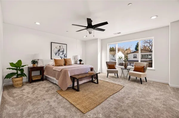 a bedroom with a bed a large window and potted plant