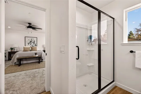 a bedroom with a bed a mirror and a glass door shower