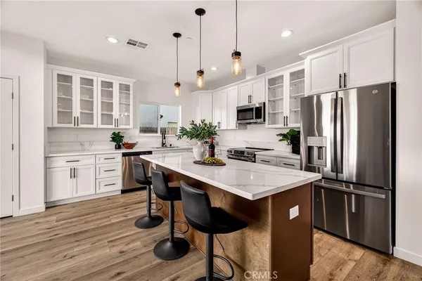 a kitchen with stainless steel appliances a stove a refrigerator a sink and a refrigerator with wooden floor