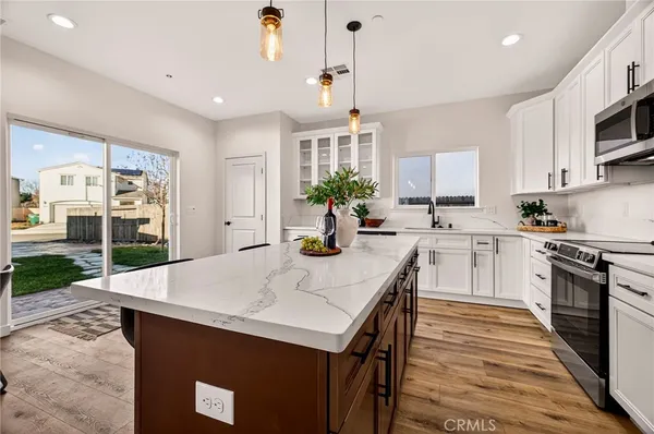 a large kitchen with kitchen island a stove a sink a refrigerator and a dining table with wooden floor