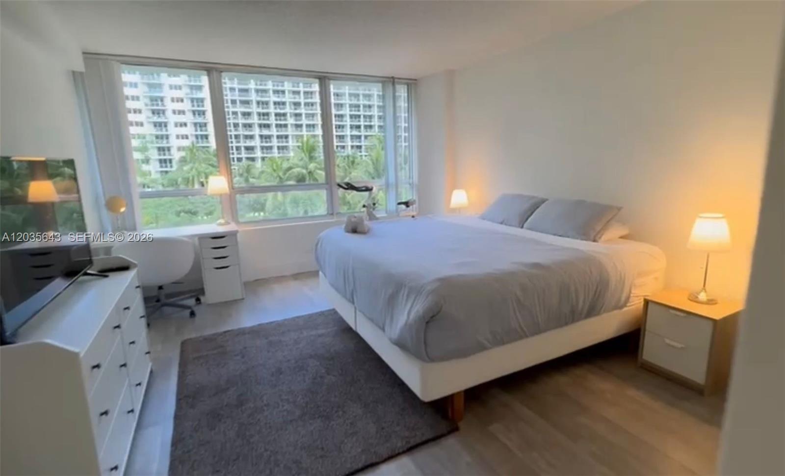 1500 Bay Road, Unit 450S Miami Beach, FL 33139 - Photo 6 of 22 a bedroom with a bed and large windows
