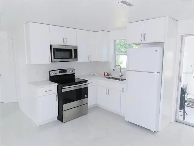 a kitchen with white cabinets and white appliances