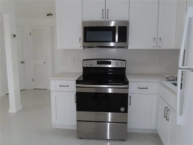 a kitchen with stainless steel appliances granite countertop white cabinets a microwave a sink and a counter