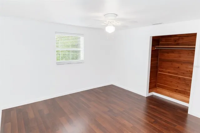 an empty room with wooden floor closet and windows