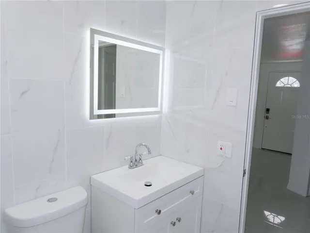 a bathroom with a toilet a sink a mirror and vanity