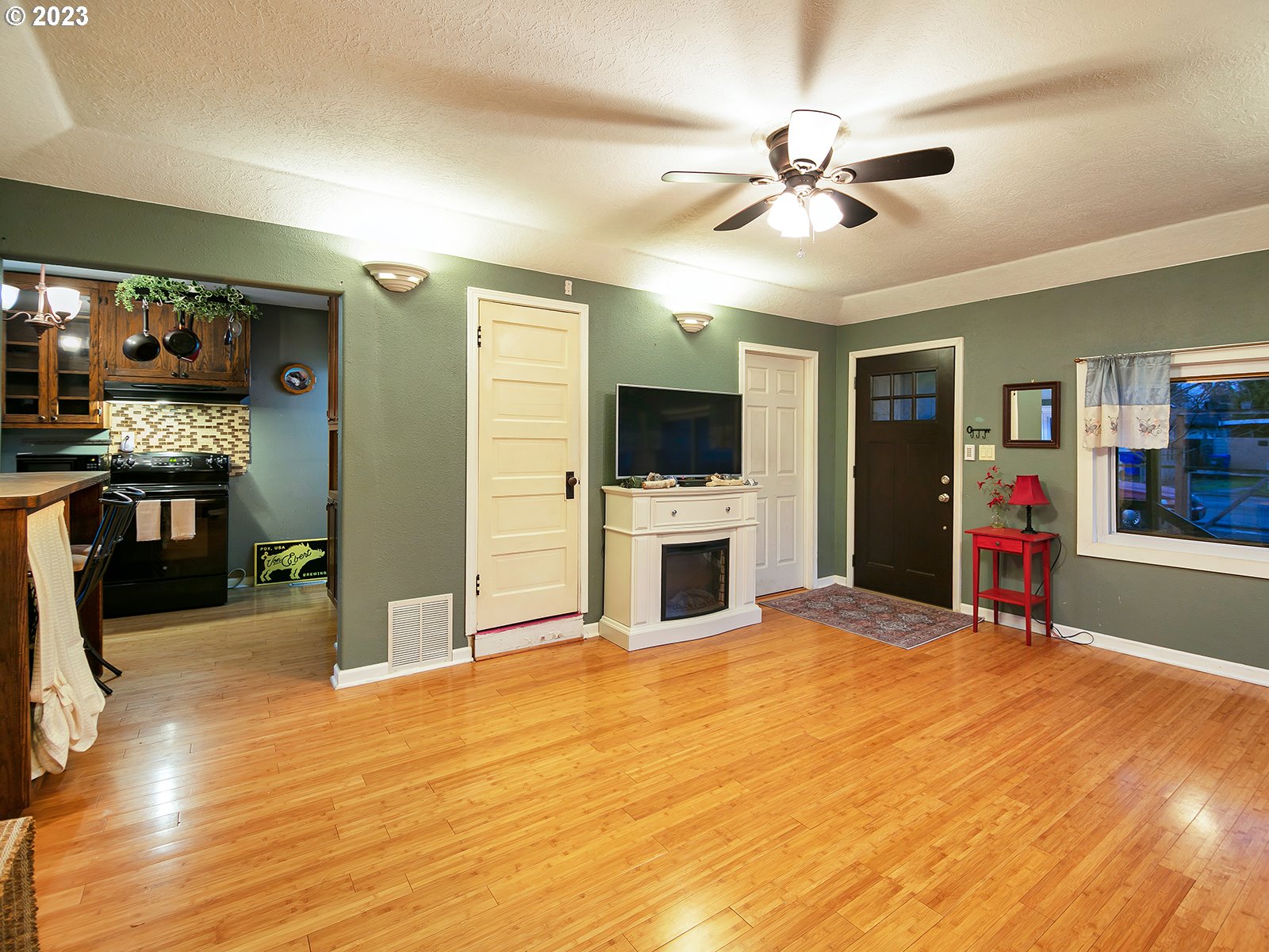 8034 Southeast Henderson Street Portland, OR 97206 - Photo 9 of 23 a view of a livingroom with a fireplace a ceiling fan and wooden floor