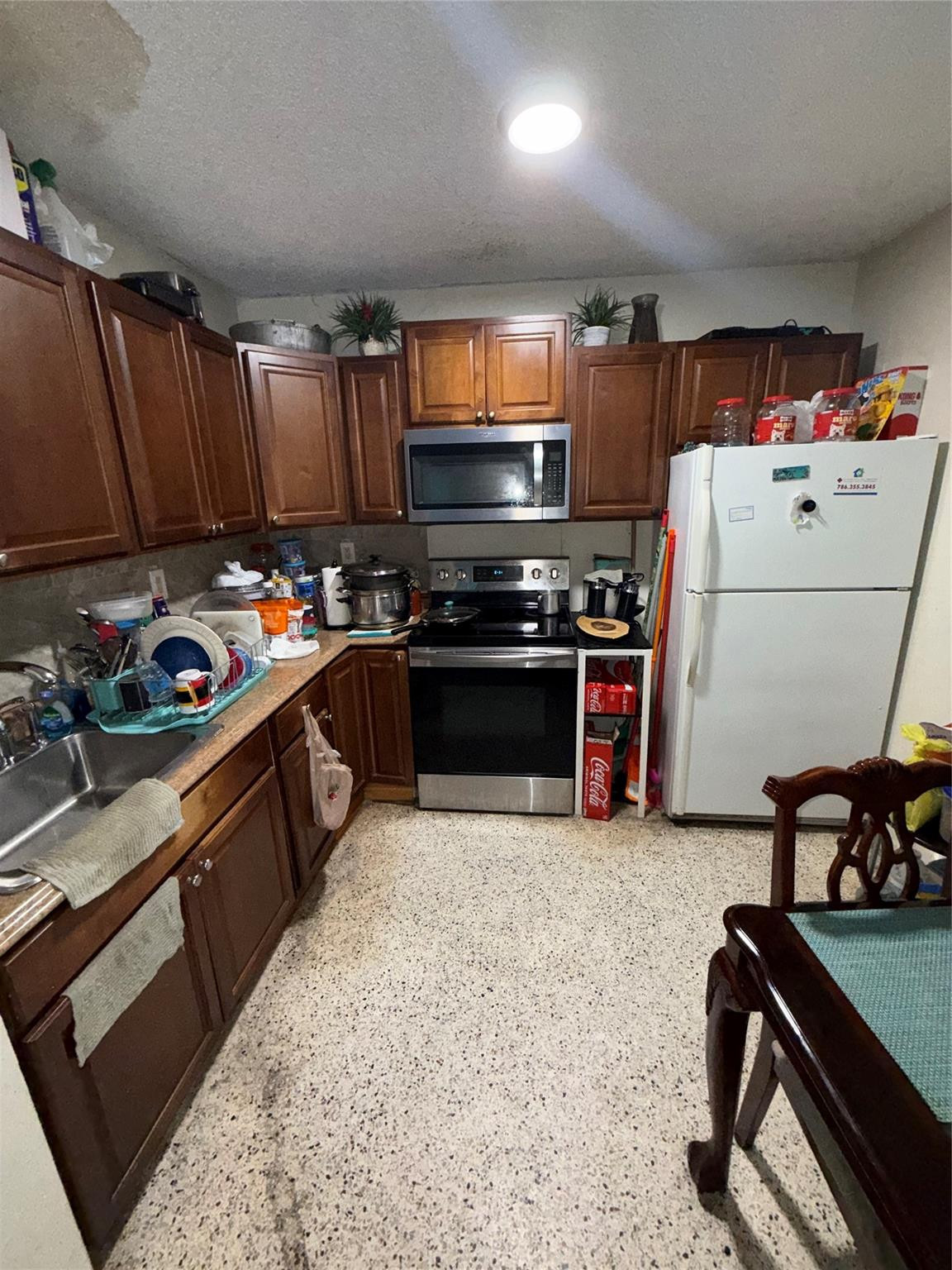1028 Northwest 24th Street Miami, FL 33127 - Photo 4 of 24 a kitchen with wooden cabinets stainless steel appliances and a counter top space