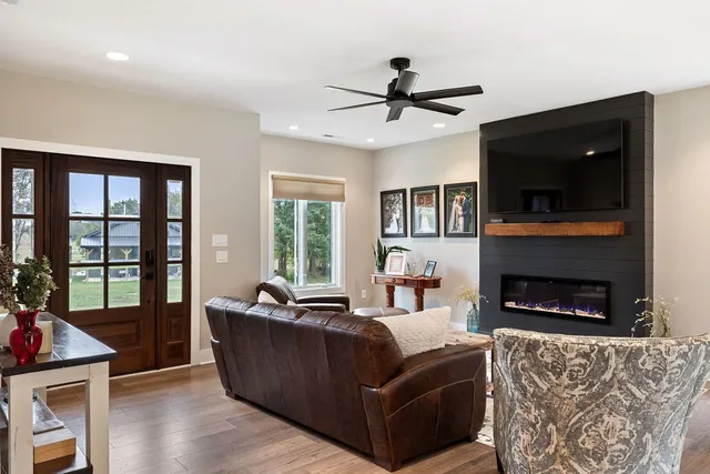a living room with furniture a ceiling fan a flat screen tv and a fireplace