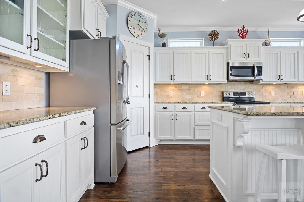 437 Atkinson Street Crystal Beach, TX 77650 - Photo 6 of 40 a kitchen with white cabinets and white appliances