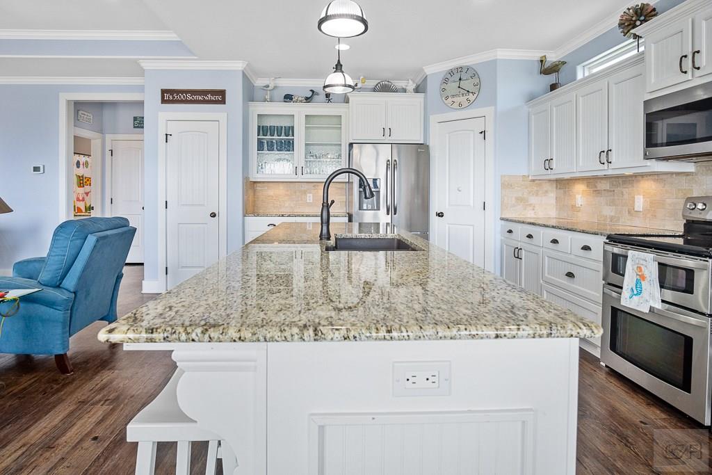 437 Atkinson Street Crystal Beach, TX 77650 - Photo 10 of 40 a kitchen with kitchen island granite countertop a stove and a white cabinets