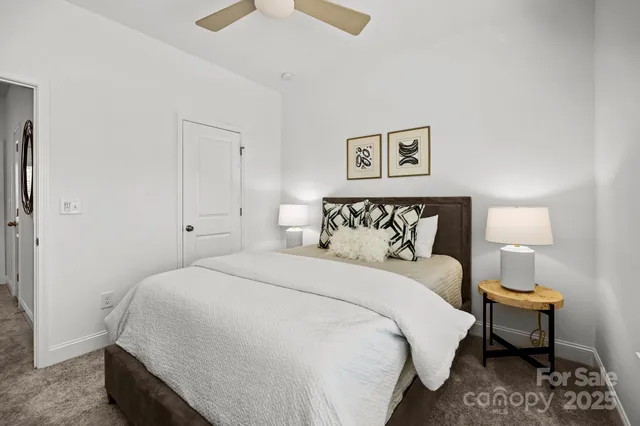 a bedroom with a bed painting on wall and a large window