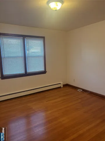 a view of an empty room with wooden floor and windows