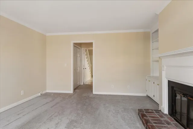 a view of an empty room with wooden floor and a fireplace