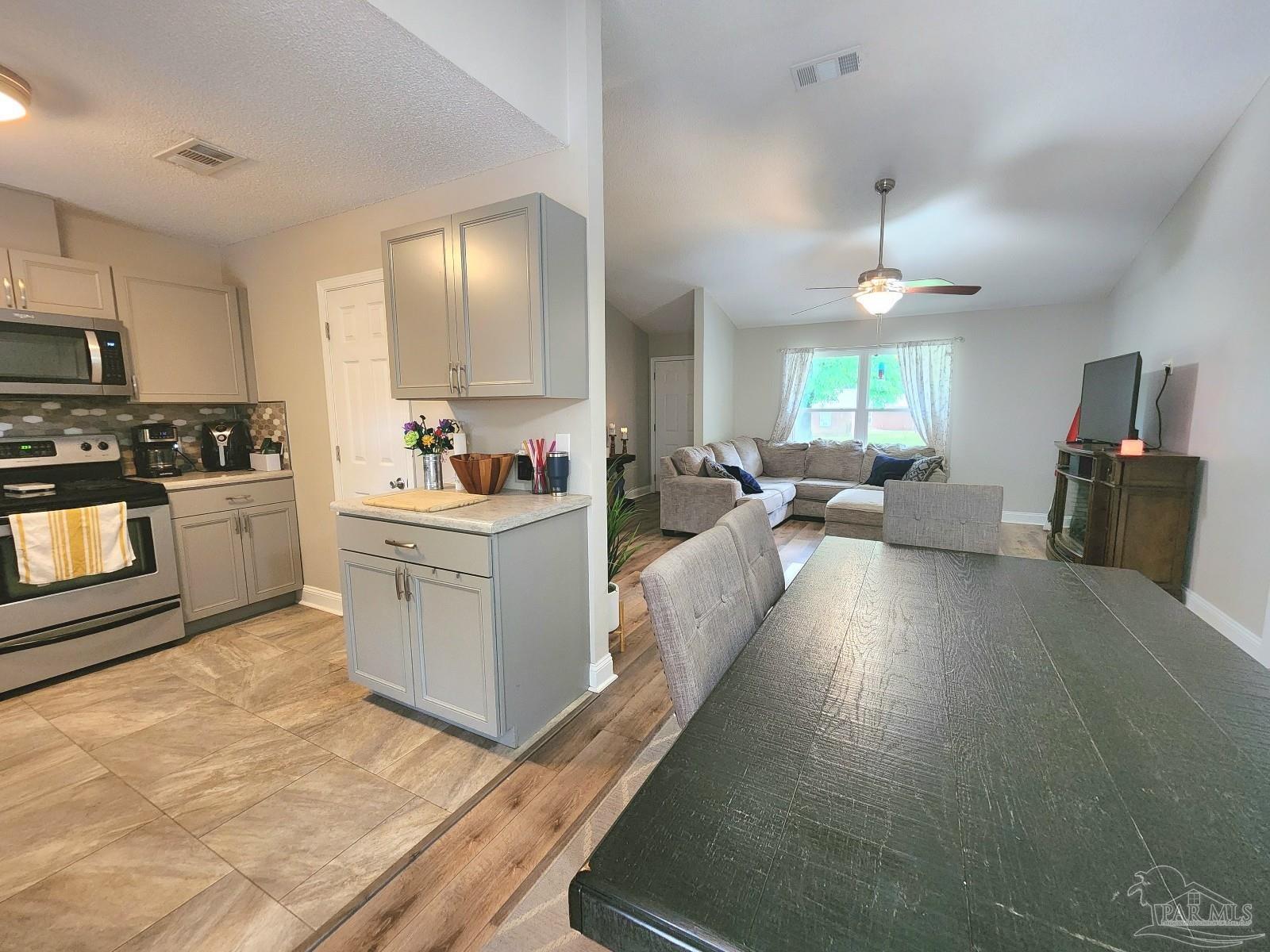 4348 Wellington Drive Pace, FL 32571 - Photo 6 of 20 a large white kitchen with kitchen island a large counter top space a sink stainless steel appliances and cabinets