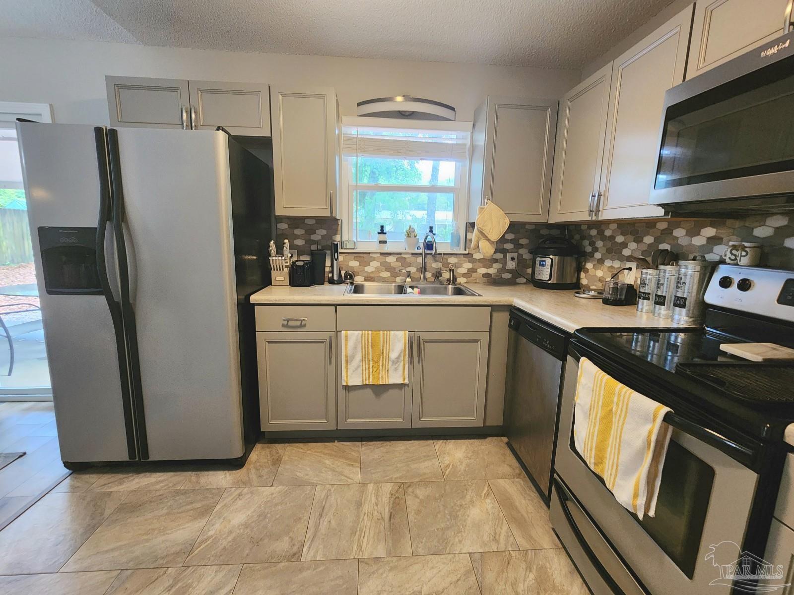 4348 Wellington Drive Pace, FL 32571 - Photo 9 of 20 a kitchen with stainless steel appliances a stove sink and refrigerator
