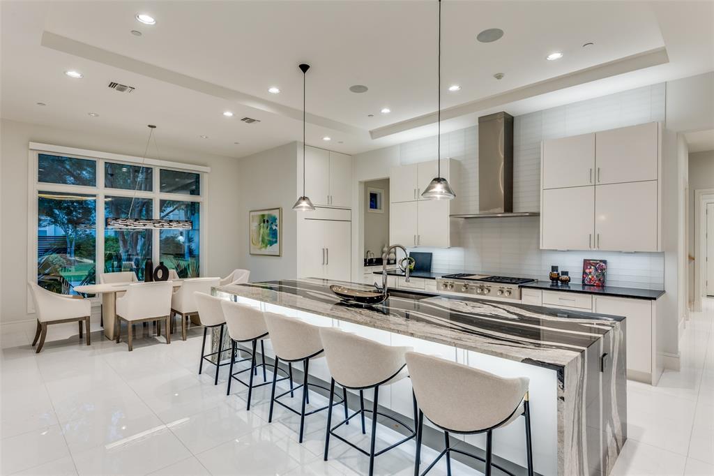 4326 Pomona Road Dallas, TX 75209 - Photo 5 of 31 Kitchen featuring dark stone counters, a kitchen bar, wall chimney range hood, hanging light fixtures, and recessed lighting