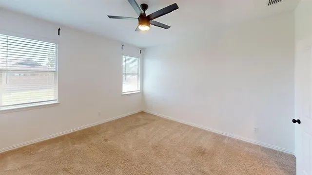 an empty room with windows and fan